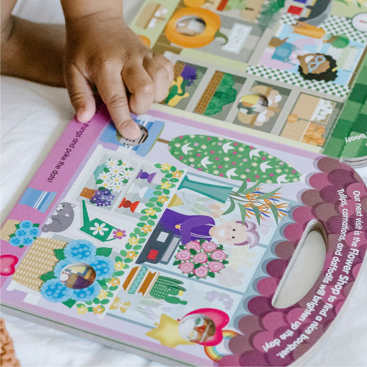 A kid playing with the Melissa & Doug Children’s Book – Poke-a-Dot: All Around Our Town