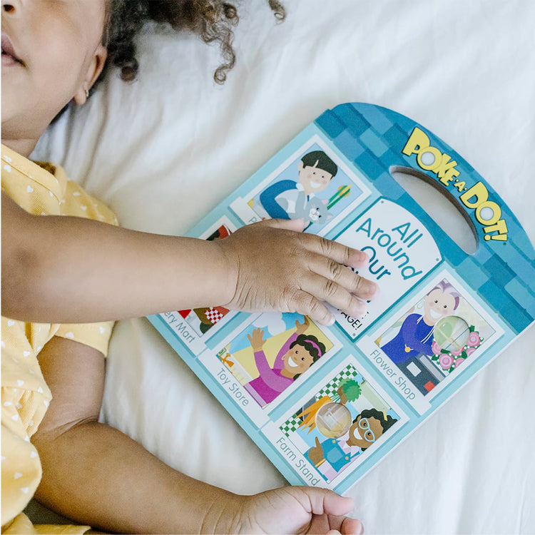A kid playing with the Melissa & Doug Children’s Book – Poke-a-Dot: All Around Our Town
