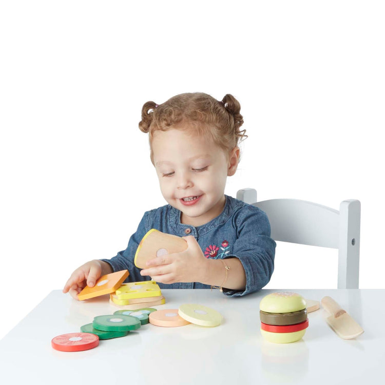 A child on white background with the Melissa & Doug Wooden Sandwich-Making Pretend Play Food Set