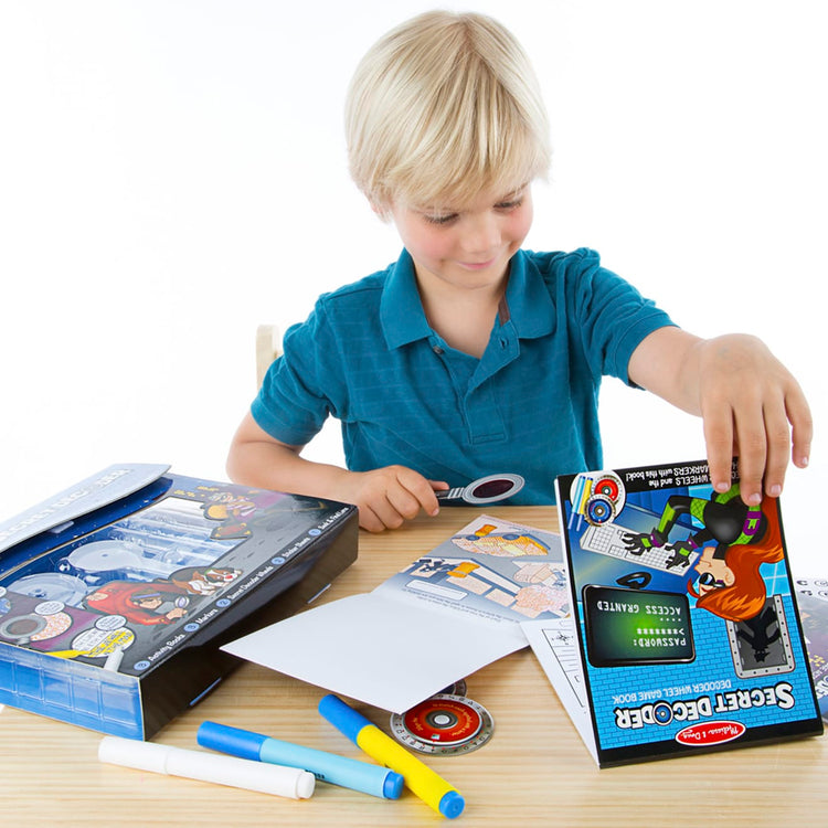A child on white background with the Melissa & Doug On the Go Secret Decoder Deluxe Activity Set and Super Sleuth Toy