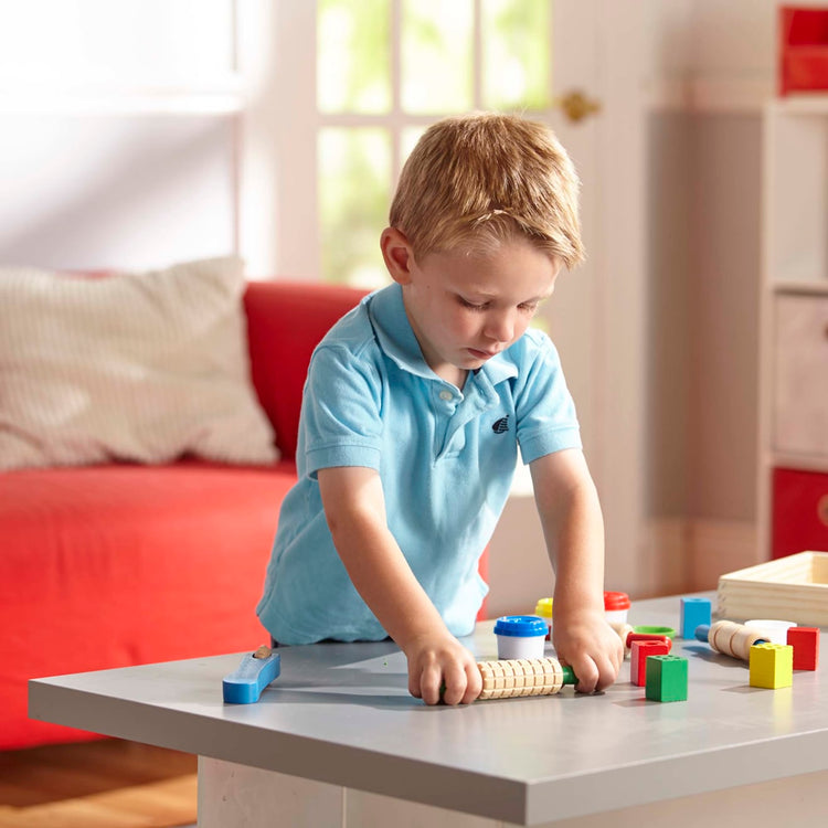 A kid playing with the Melissa & Doug Shape, Model, and Mold Clay Activity Set - 4 Tubs of Modeling Dough and Tools