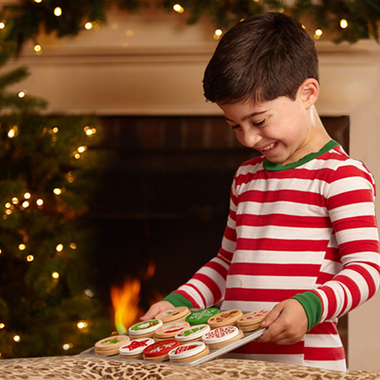 A kid playing with the Melissa & Doug Slice and Bake Wooden Christmas Cookie Play Food Set