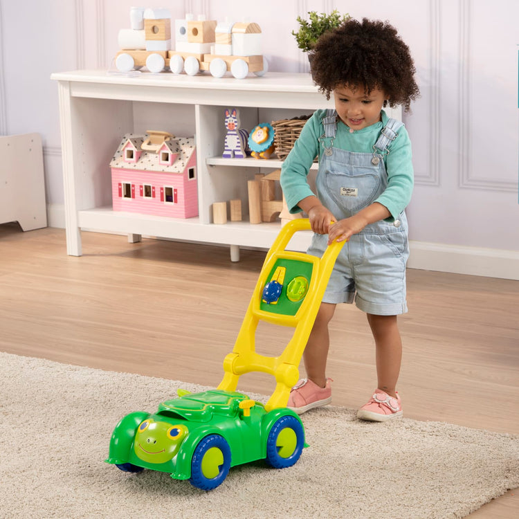 A kid playing with the Melissa & Doug Sunny Patch Snappy Turtle Lawn Mower - Pretend Play Toy for Kids