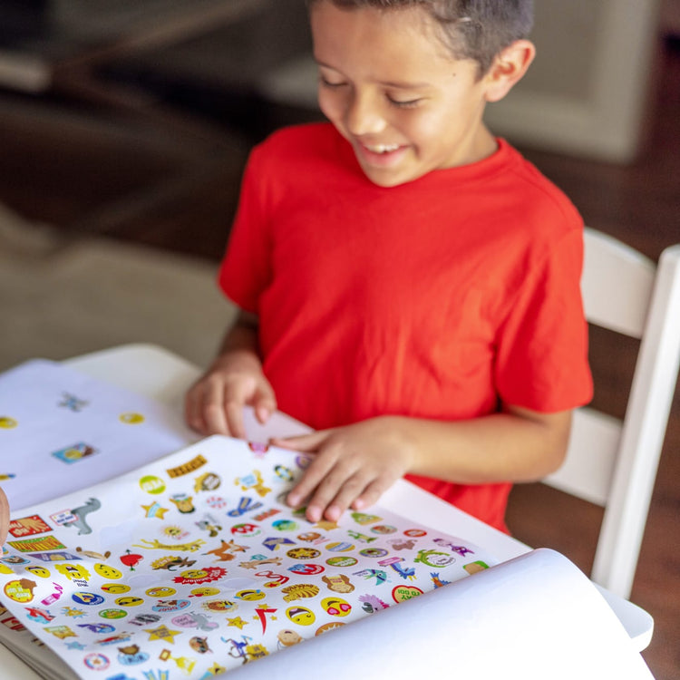 A kid playing with the Melissa & Doug Sticker Collection Book: 1,000+ Stickers – Seasons and Celebrations
