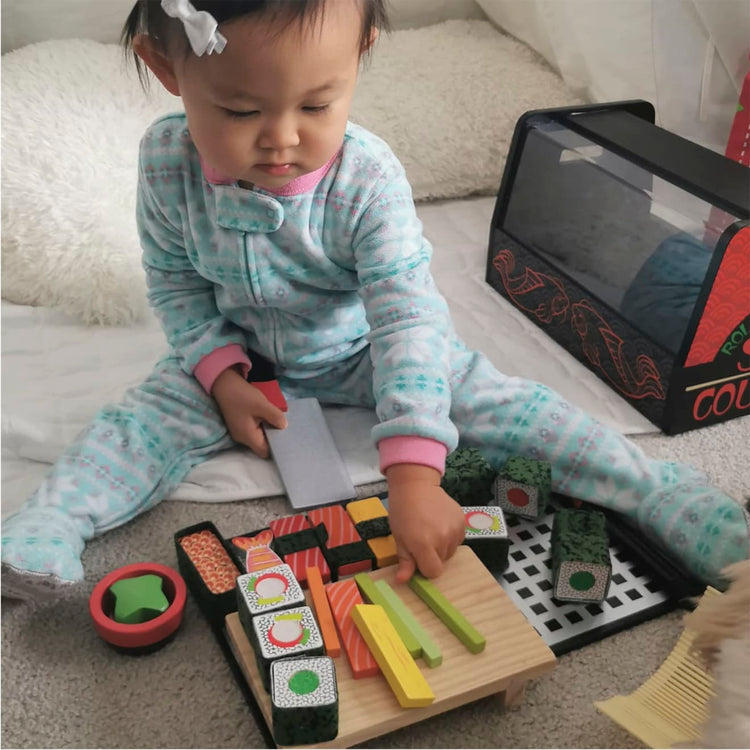 A kid playing with the Melissa & Doug Sushi Slicing Wooden Play Food Set