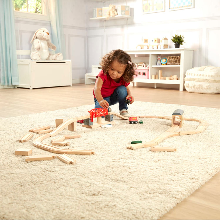 A kid playing with the Melissa & Doug Swivel Bridge Wooden Train Set (47 pcs)