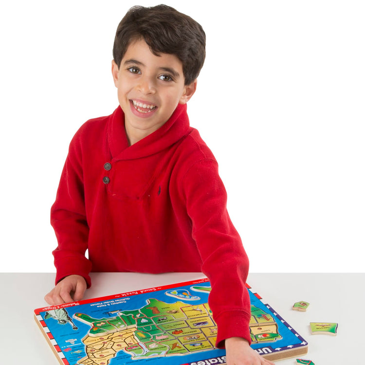 A child on white background with the Melissa & Doug USA Map Sound Puzzle - Wooden Puzzle With Sound Effects (40 pcs)