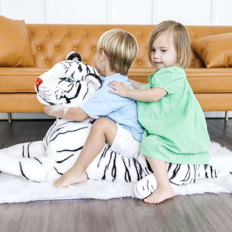 A kid playing with the Melissa & Doug Giant Siberian White Tiger - Lifelike Stuffed Animal (over 5 feet long)