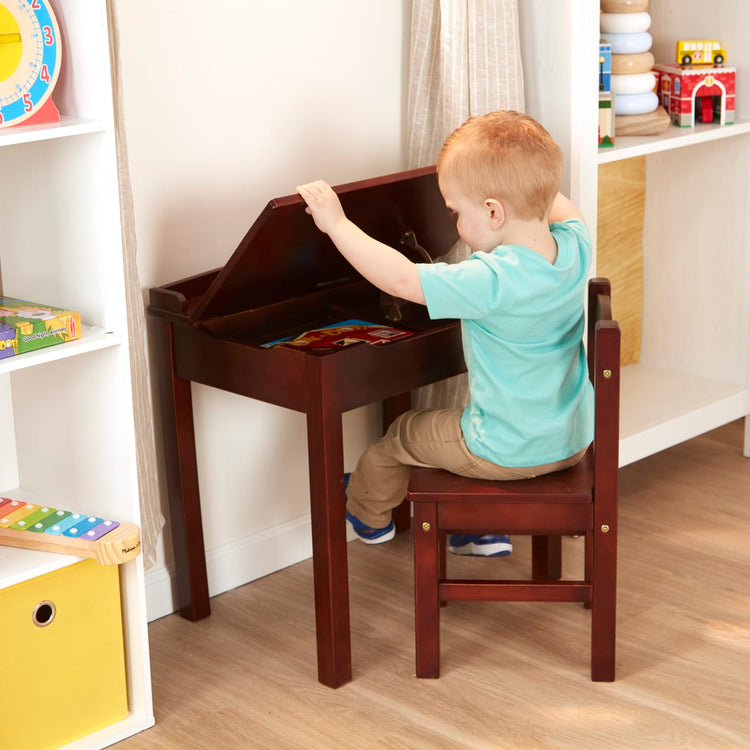 A kid playing with the Melissa & Doug Wooden Child's Lift-Top Desk & Chair - Espresso