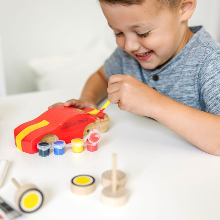 A kid playing with the Melissa & Doug Decorate-Your-Own Wooden Race Car Craft Kit