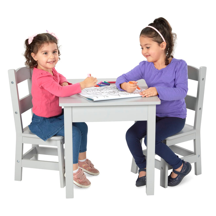 A child on white background with the Melissa & Doug Kids Furniture Wooden Table and 2 Chairs - Gray