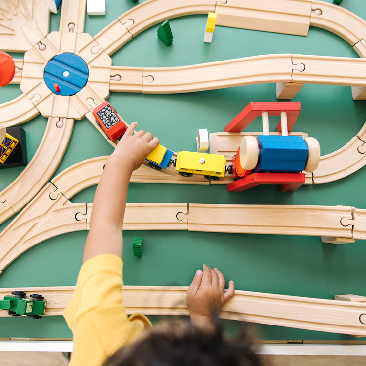 image of child playing with wooden train track toy