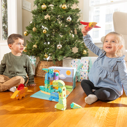 Melissa & Doug Best Holiday Wooden Toys & Gifts for Kids blog post kids playing under Christmas tree