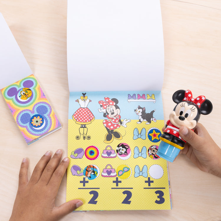 A kid playing with The Melissa & Doug Sticker WOW!™ Disney Minnie Mouse Bundle: 24-Page Activity Pad, Sticker Stamper, 500 Stickers, Mini Pad, Arts and Crafts Fidget Toy Collectible Character