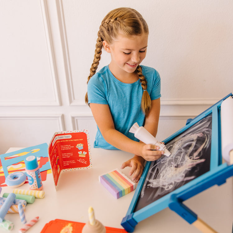 A kid playing with The Melissa & Doug Sweet Shop Multi-Colored Chalk and Holders Play Set - 33 Pieces, Great Gift for Girls and Boys