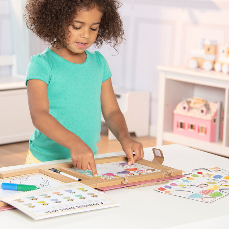 A kid playing with The Melissa & Doug Natural Play: Play, Draw, Create Reusable Drawing & Magnet Kit – Princesses (54 Magnets, 5 Dry-Erase Markers)
