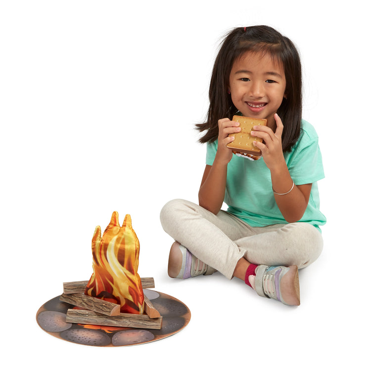 A child on white background with The Melissa & Doug Let's Explore Campfire S'Mores Play Set