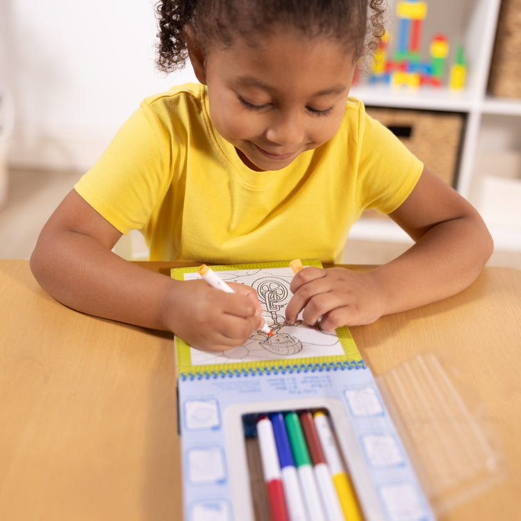 A kid playing with The Melissa & Doug On the Go Color by Numbers Kids' Design Boards: Playtime, Construction, Sports, and More