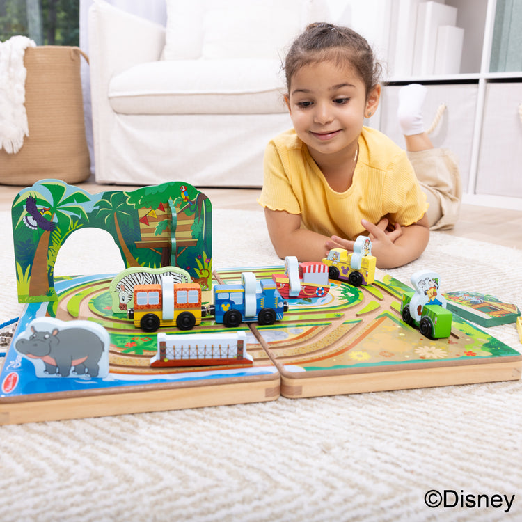 A kid playing with The Melissa & Doug Disney Take-Along Safari Adventure Wooden Play Set with Built-In Tracks – 20 Pieces | Mickey Mouse, Minnie, Wooden Toy for Boys and for Girls 3+