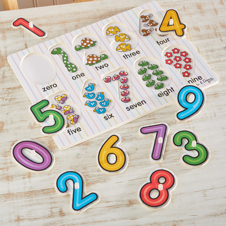 A playroom scene with The Melissa & Doug Lift & See Numbers Wooden Peg Puzzle - 10 Pieces
