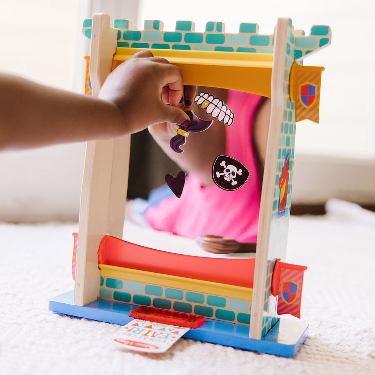 A kid playing with The Melissa & Doug Fun at the Fair! Wooden Double-Sided Funhouse Mirror