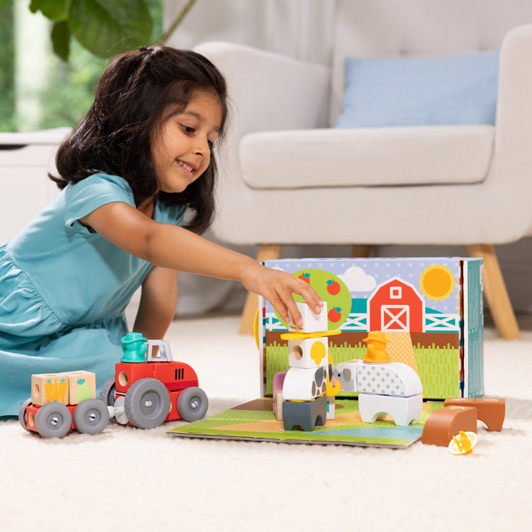 A kid playing with The Melissa & Doug Blockables™ Farm and Farm Friends 2-Pack Bundle Connectable Wooden Building Blocks Preschool Play Set Toy