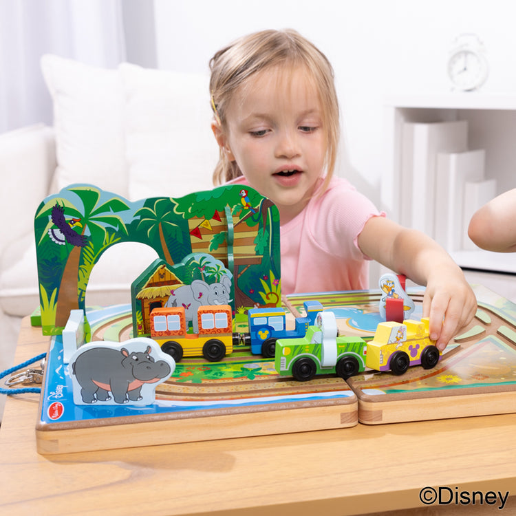 A kid playing with The Melissa & Doug Disney Take-Along Safari Adventure Wooden Play Set with Built-In Tracks – 20 Pieces | Mickey Mouse, Minnie, Wooden Toy for Boys and for Girls 3+