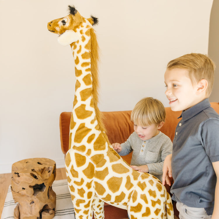 A kid playing with The Melissa & Doug Giant Giraffe - Lifelike Plush Stuffed Animal (over 4 feet tall)
