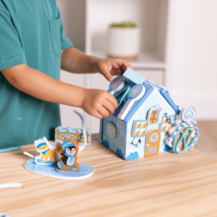 A kid playing with The Melissa & Doug Winter Frost Wooden Gingerbread House Play Set for Boys and Girls 3+ 