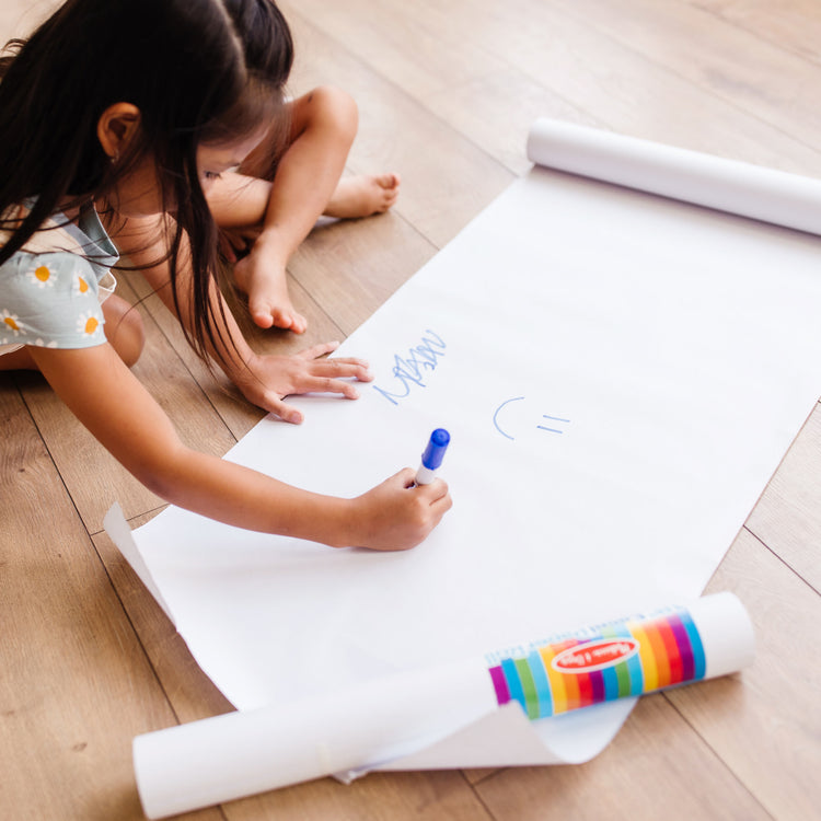 A kid playing with The Melissa & Doug Easel Paper Roll - 17 Inches Wide, 75 Feet Long for Painting, Drawing, Art and Craft Projects for Kids