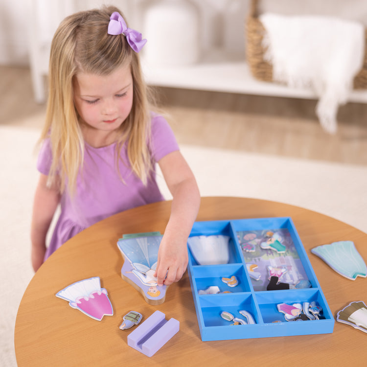 A kid playing with The Melissa & Doug Disney Princess Cinderella Magnetic Dress-Up Wooden Doll Pretend Play Set (30+ pcs)
