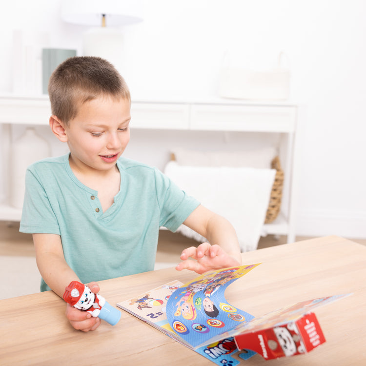 A kid playing with The Melissa & Doug Sticker WOW!™ 24-Page Activity Pad and Sticker Stamper, 300 Stickers, Arts and Crafts Fidget Toy Collectible Character – PAW Patrol Marshall