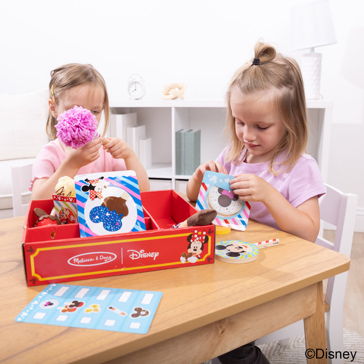 A kid playing with The Melissa & Doug Disney Snacks & Popcorn Wooden Play Food Set – 24 Pieces | Mickey Mouse, Minnie, Wooden Toy for Boys and for Girls 3+