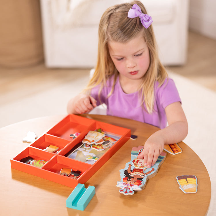 A kid playing with The Melissa & Doug Disney Princess Moana Magnetic Dress-Up Wooden Doll Pretend Play Set (30+ pcs)
