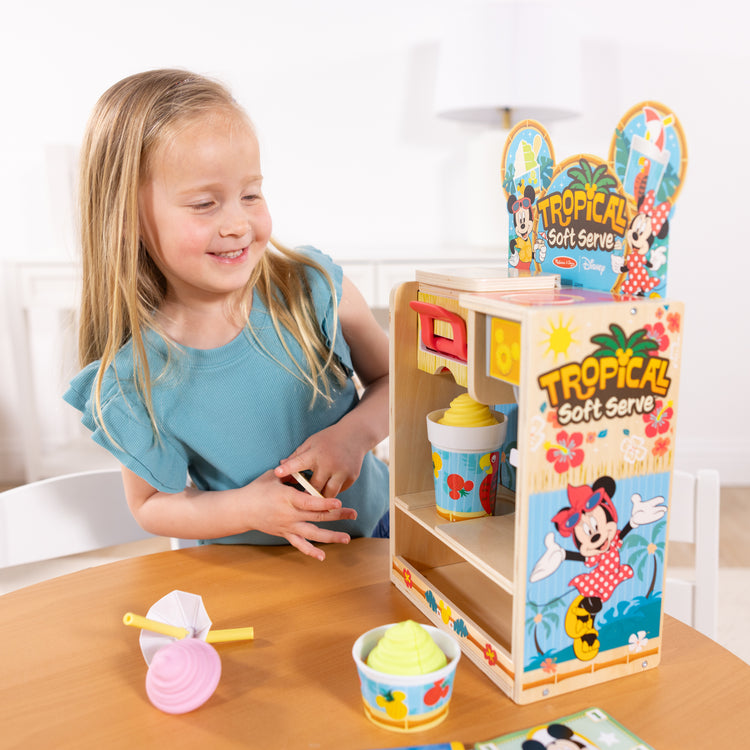 A kid playing with The Disney Tropical Soft Serve Ice Cream Wooden Play Food Set – 23 Pieces | Mickey Mouse, Minnie, Wooden Toy for Boys and for Girls 3+