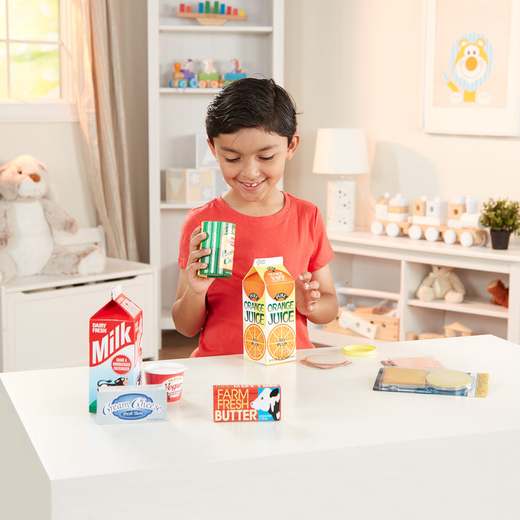 A kid playing with The Melissa & Doug Fridge Groceries Play Food Cartons (8 pieces)