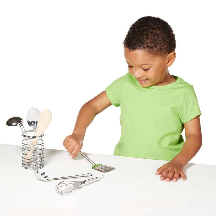 A child on white background with The Melissa & Doug Stir and Serve Cooking Utensils (7 pcs) - Stainless Steel and Wood