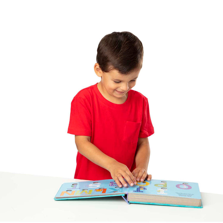 A child on white background with The Melissa & Doug Children's Book - Poke-a-Dot: An Alphabet Eye Spy (Board Book with Buttons to Pop)