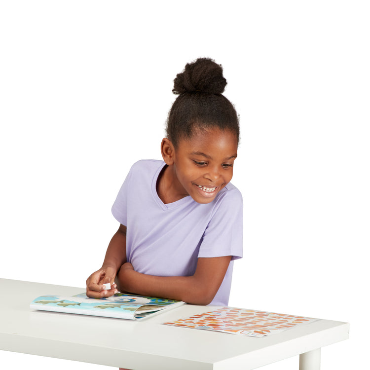 A child on white background with The Melissa & Doug Mosaic Sticker Pad Ocean Animals (12 Color Scenes to Complete with 850+ Stickers)