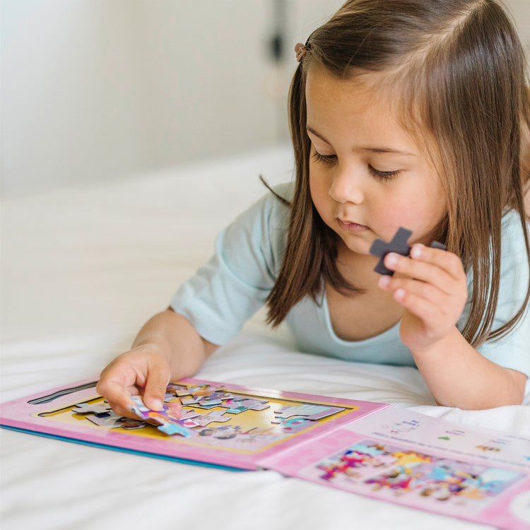 A kid playing with The Melissa & Doug Take-Along Magnetic Jigsaw Puzzles Travel Toy – Princesses (2 15-Piece Puzzles)