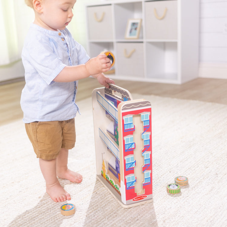 A kid playing with The Melissa & Doug GO Tots Wooden Town House Tumble with 6 Disks