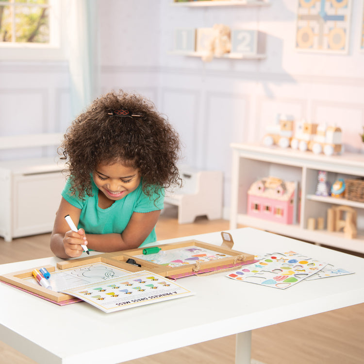 A kid playing with The Melissa & Doug Natural Play: Play, Draw, Create Reusable Drawing & Magnet Kit – Princesses (54 Magnets, 5 Dry-Erase Markers)