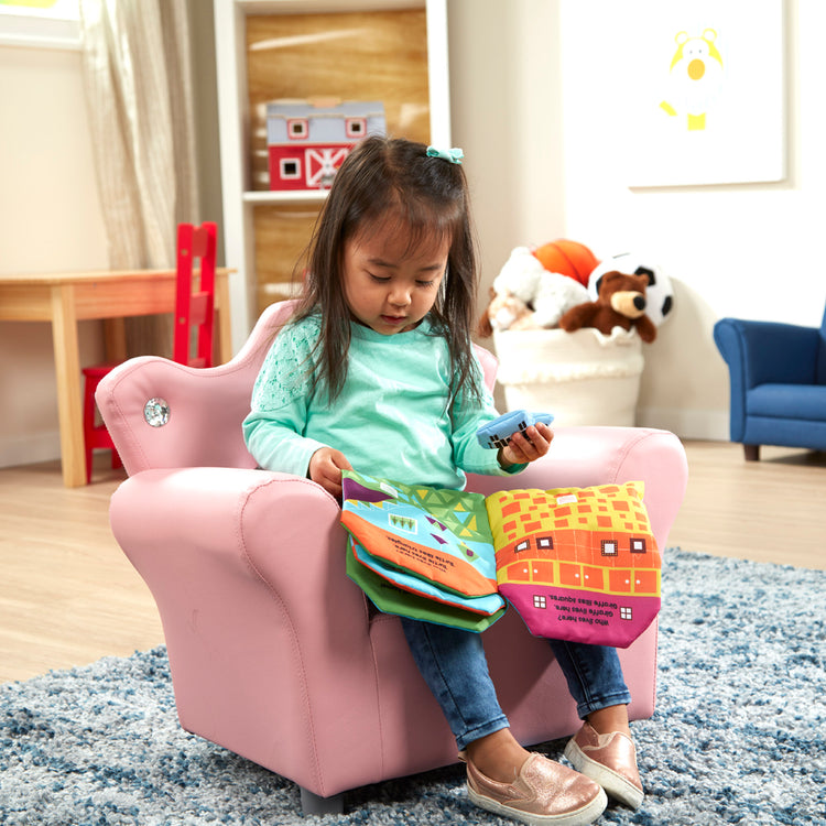 A kid playing with The Melissa & Doug Pink Faux Leather Child’s Crown-Back Armchair (Kid’s Furniture)