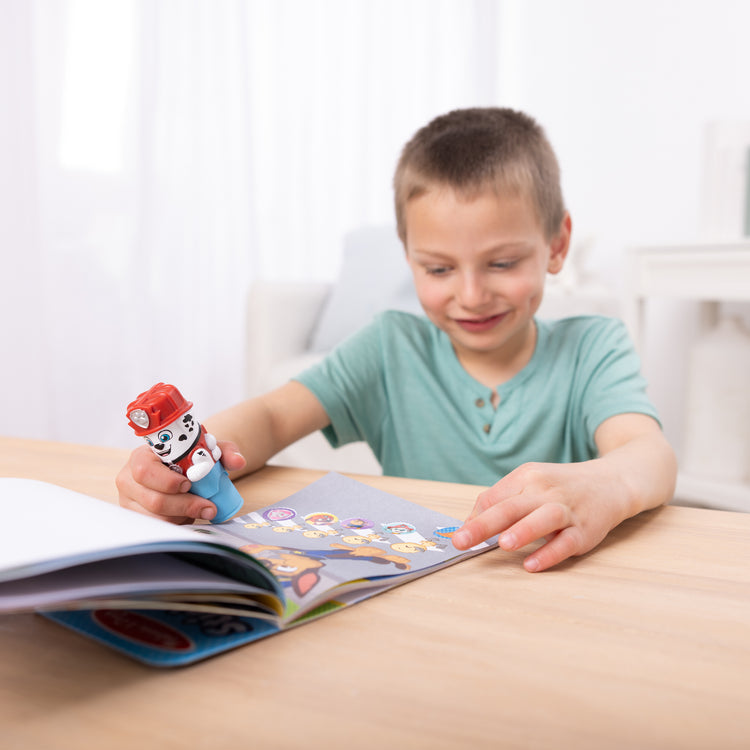 A kid playing with The Melissa & Doug Sticker WOW!™ PAW Patrol Marshall Bundle: 24-Page Activity Pad, Sticker Stamper, 500 Stickers, Mini Pad, Arts and Crafts Fidget Toy Collectible Character