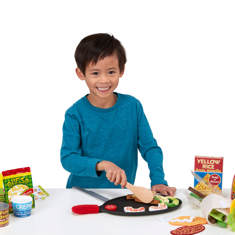 A child on white background with The Melissa & Doug Fill & Fold Taco & Tortilla Set, 43 Pieces – Sliceable Wooden Mexican Play Food, Skillet, and More