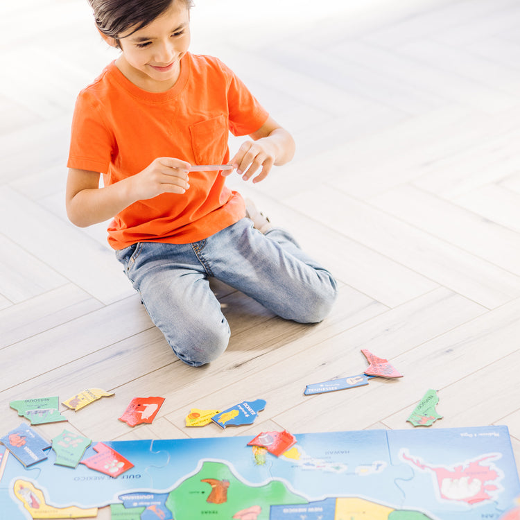 A kid playing with The Melissa & Doug USA Map Floor Puzzle - 51 Pieces (2 x 3 feet)