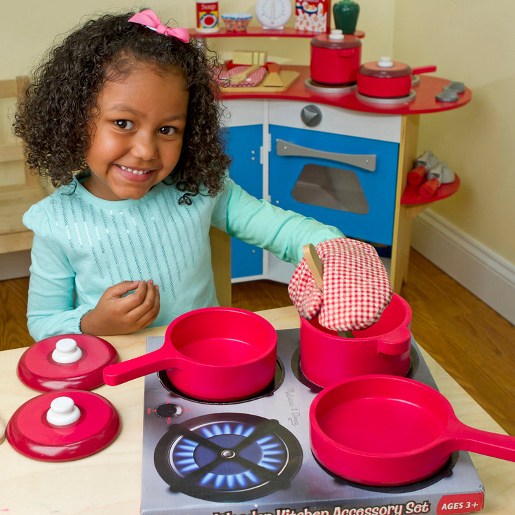 A kid playing with The Melissa & Doug Deluxe Wooden Kitchen Accessory Play Set - Pots & Pans (8 pcs)