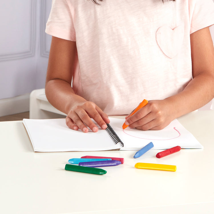 A kid playing with The Melissa & Doug Mini-Sketch Spiral-Bound Pad (6 x 9 inches) - 4-Pack