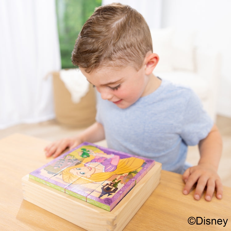 A kid playing with The Melissa & Doug Disney Princess Wooden Toy Cube Puzzle Blocks for Boys and for Girls 3+