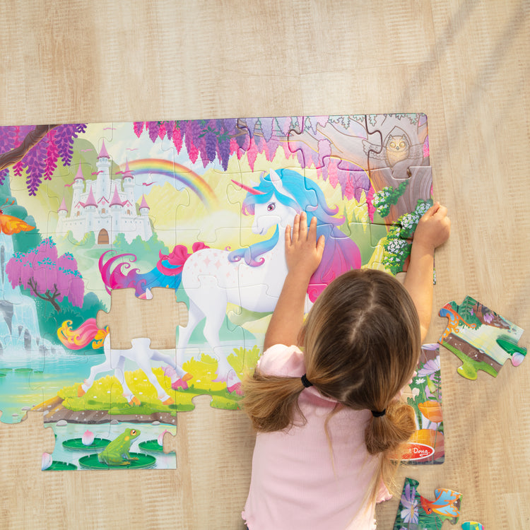 A kid playing with The Melissa & Doug Glow-in-the-Dark Unicorn Jumbo Floor Puzzle, 48-Piece Jigsaw Puzzle with Hidden Details, Kids Puzzles for Girls & Boys Ages 4 and Up